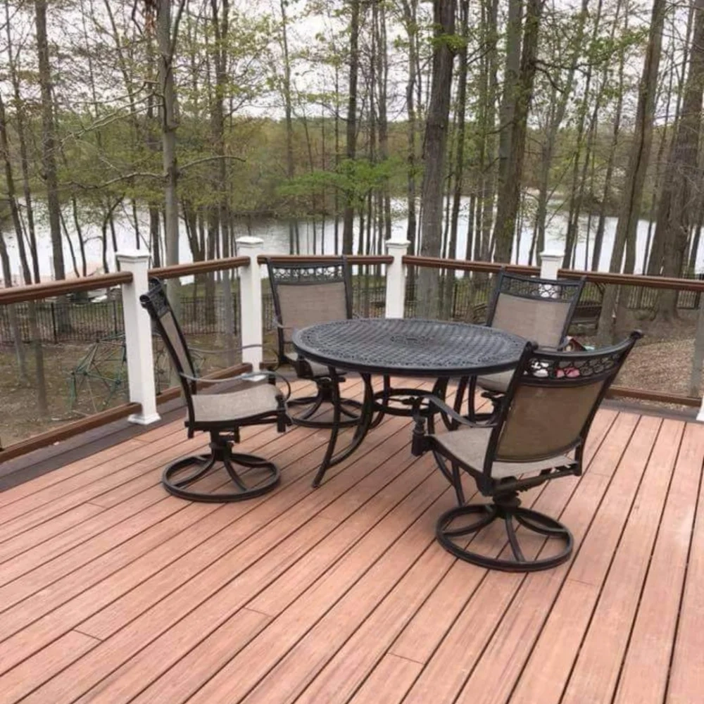 Table and Chairs are Arranged on a Deck Surrounded by Trees